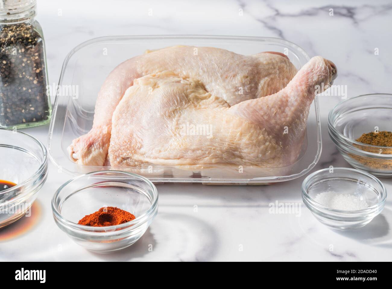 Rohes Hühnerfleisch und Zutaten für die Marinade: Paprika, Gewürze, Salz, Sojasauce und Gewürze in der Nähe auf Marmorboden Stockfoto