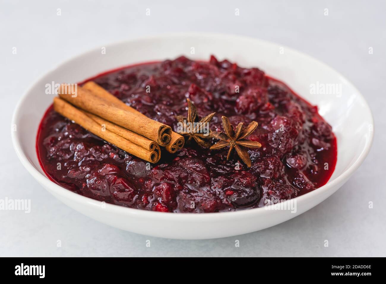 Cranberry-Sauce, Zimt, Anis-Stern aus nächster Nähe in einer Schüssel auf hellem Hintergrund Stockfoto