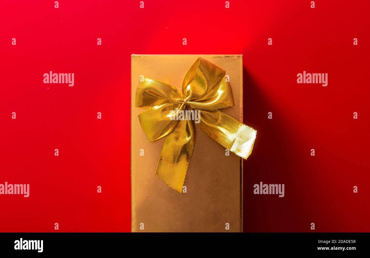 Geschenk in goldener Verpackung mit Schleife auf rotem Hintergrund Stockfoto