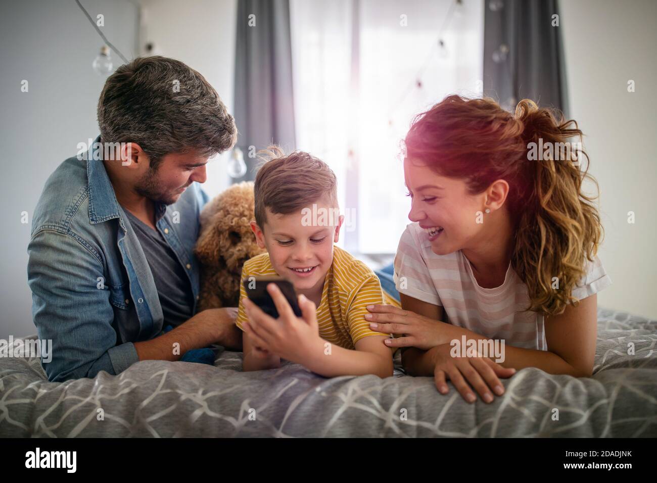 Glückliche Familie, die digitale Technologie-Dekore für das Spielen von Filmen verwendet, um zu Hause zu entspannen. Stockfoto