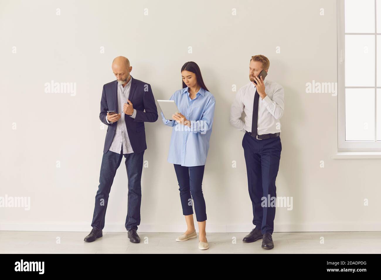 Ernst beschäftigt multiethnischen Menschen in verschiedenen Altersgruppen mit modernen Gadgets Beim Warten in der Schlange Stockfoto