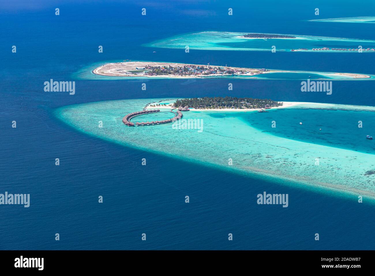 Luftaufnahme einer tropischen Insel im türkisfarbenen Wasser. Luxuriöse Villen über dem Wasser auf tropischen Insel Resort. Malediven Luftbild Landschaft Urlaub Stockfoto