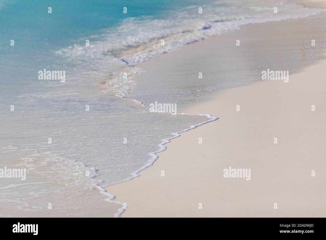 Blaue Ozean Wellen Sonnenlicht Reflexion Sand Strand Hintergrund. Ruhige Wellen auf weißem Sand, sonniges tropisches Wetter, sommerliche Stimmung Stockfoto
