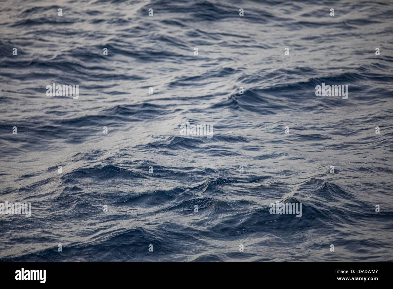 Blaue Meeresoberfläche mit hellen Wellen. Hintergrundstruktur eines ruhigen tiefblauen Ozeans mit Wellen auf der Oberfläche des Meerwassers Stockfoto