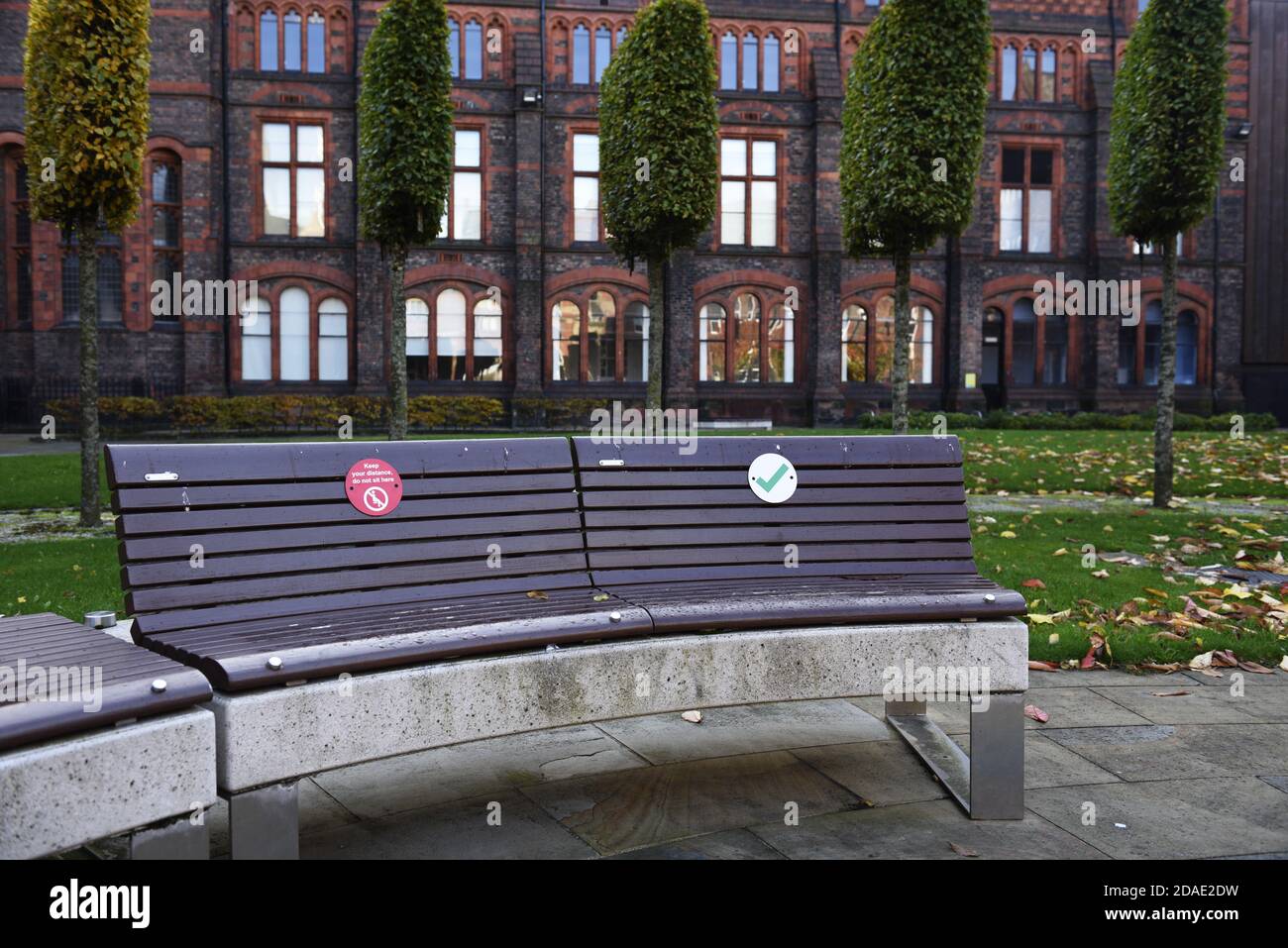 Soziale Distanzierungszeichen auf Bänken zur Förderung der sozialen Distanzierung auf dem Campus der Universität Liverpool, aufgrund des Coronavirus, covid 19 Pandemie Stockfoto