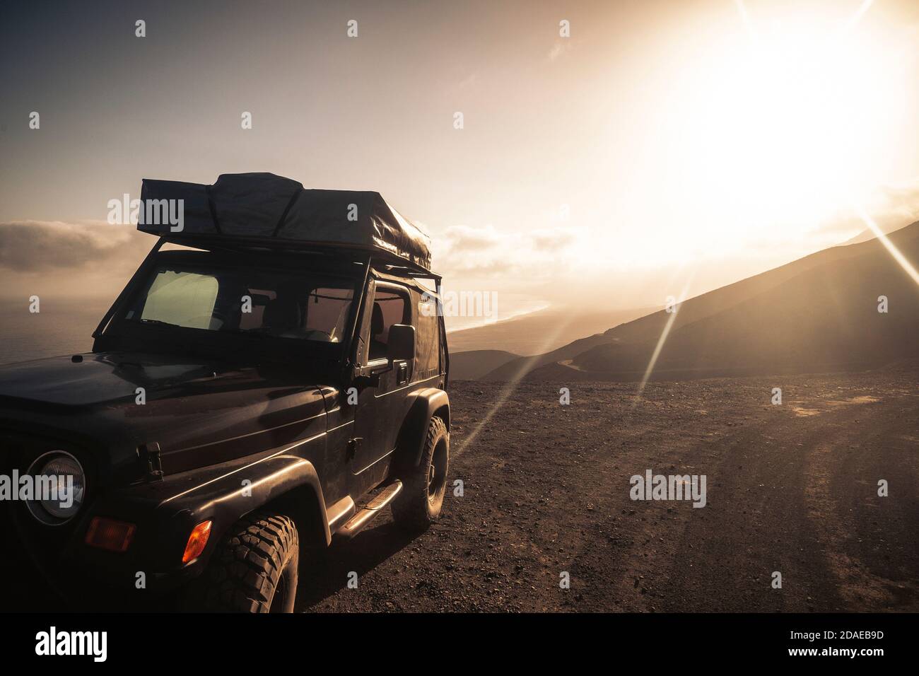 Reisen Sie mit Auto und Zelt auf dem Dach zu leben Abenteuer und erkunden Sie die Welt - wilde Orte und Alternative Fahrzeug Reise, um totale Freiheit mit niemand - Berge zu genießen Im Hintergrund und Sonnenlicht Stockfoto