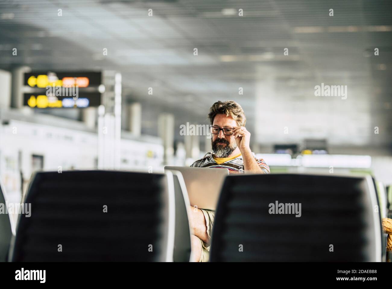 Erwachsene kaukasischen Mann arbeiten an einem Laptop-Computer wartet seine Flug am Flugsteig - Konzept des digitalen Nomaden Und Technologie Job bezogen - moderne Menschen und Internet-Verbindung Stockfoto