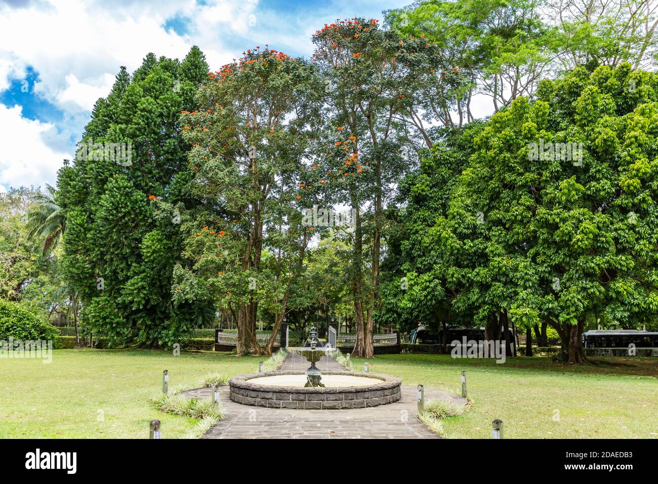 Brunnen im Garten mit Palmen und exotischen Pflanzen, afrikanische Tulpenbaum, (Spathodea companulata), Rum Destillerie Le Saint Aubin, gegründet 1819, Saint Aubin, Mauritius, Afrika, Indischer Ozean Stockfoto