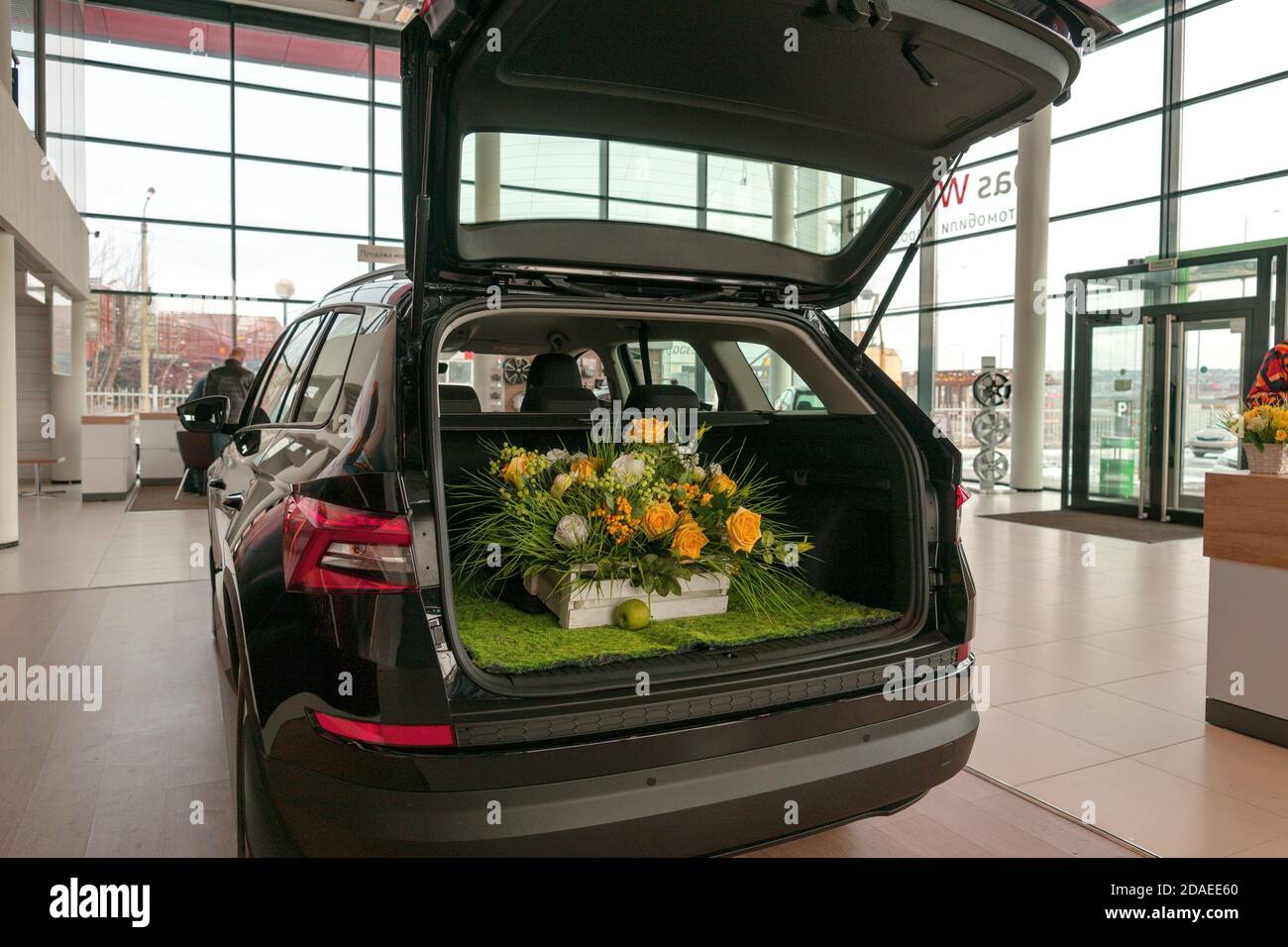 Ein Blumenkorb befindet sich im offenen Kofferraum eines Autos im Autohaus. Stockfoto