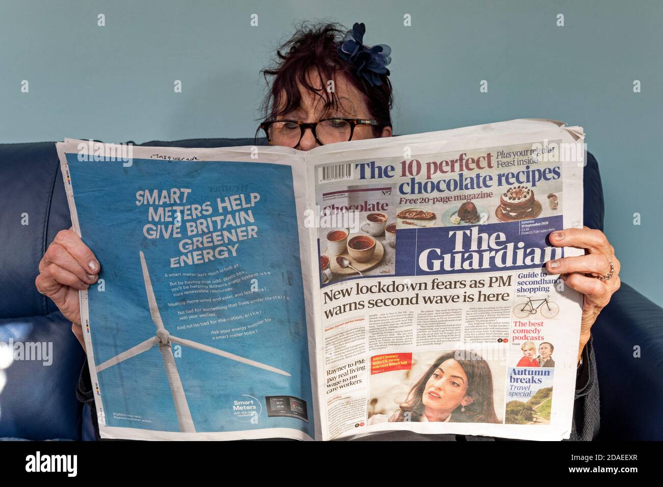 Frau beim Lesen der Guardian Zeitung mit Schlagzeilen über Coronavirus an zweiter Stelle Winken Stockfoto