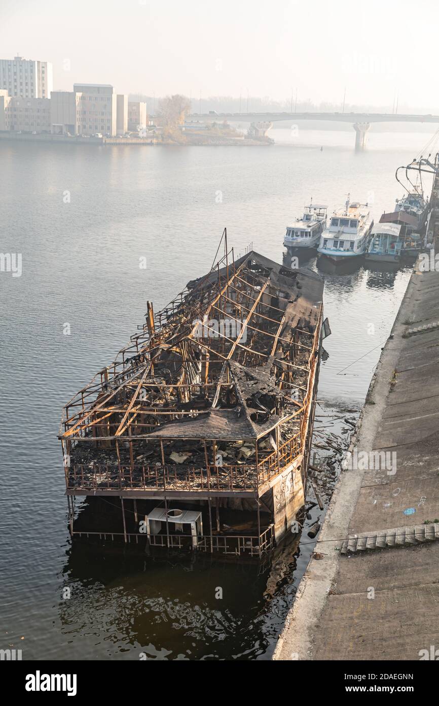 Die Überreste eines verbrannten Schiffes auf dem Fluss Dnjepr in Kiew im Podolski Bezirk. Altes verbranntes Kreuzfahrtschiff nahe Ufer des Flusses Dnepr Stockfoto