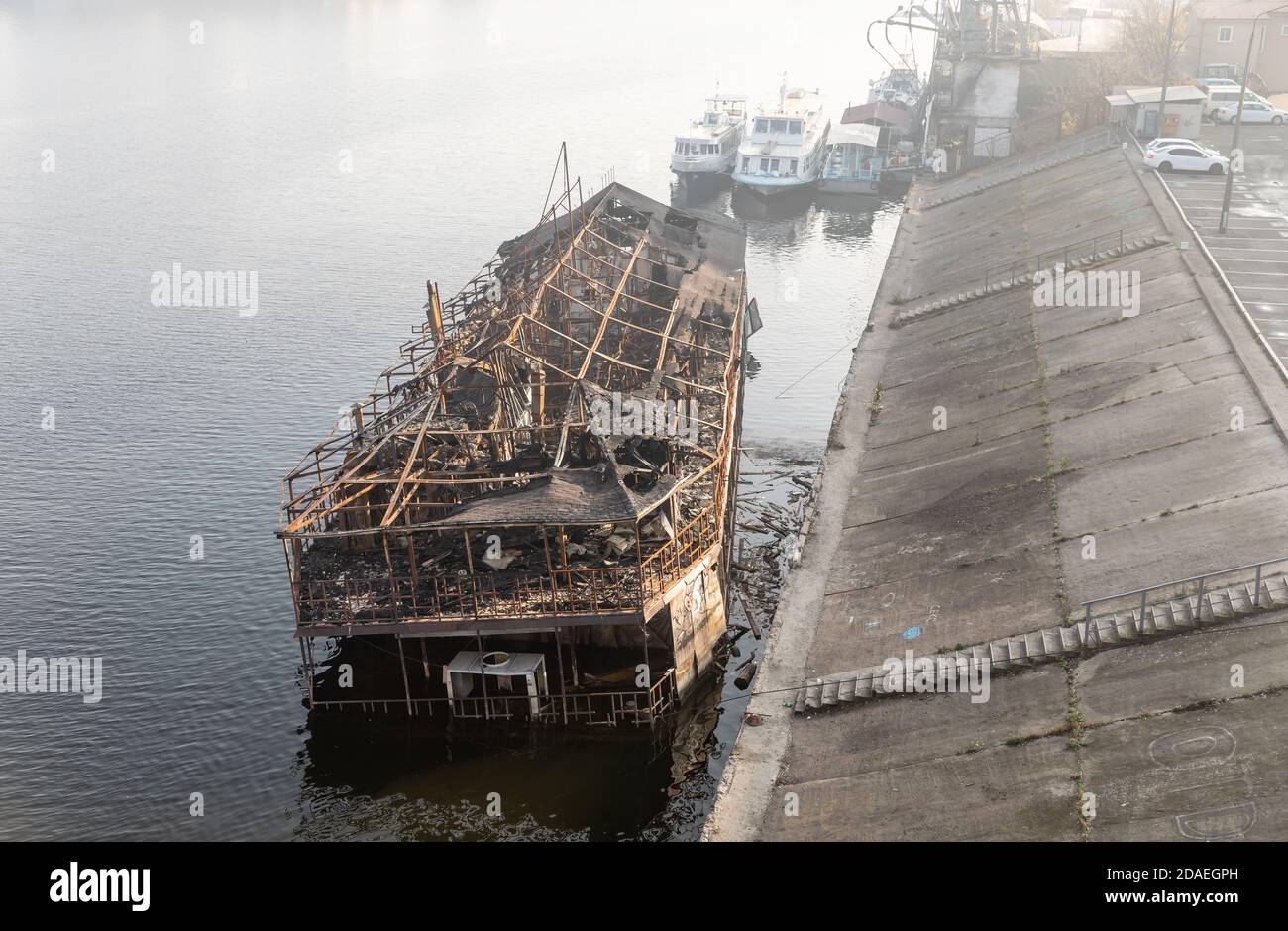 KIEW, UKRAINE - 10. Nov. 2018: Die Überreste eines verbrannten Schiffes auf dem Dnjepr in Kiew im Podolski Bezirk. Altes verbranntes Kreuzfahrtschiff in der Nähe des Ufers von Stockfoto