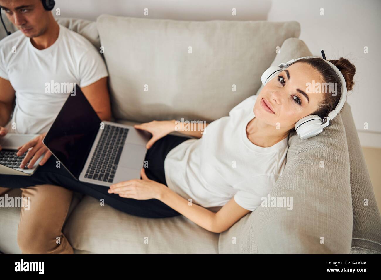 Schöne Brünette Dame liegt auf der Couch neben ihrem fokussierten Freund Stockfoto