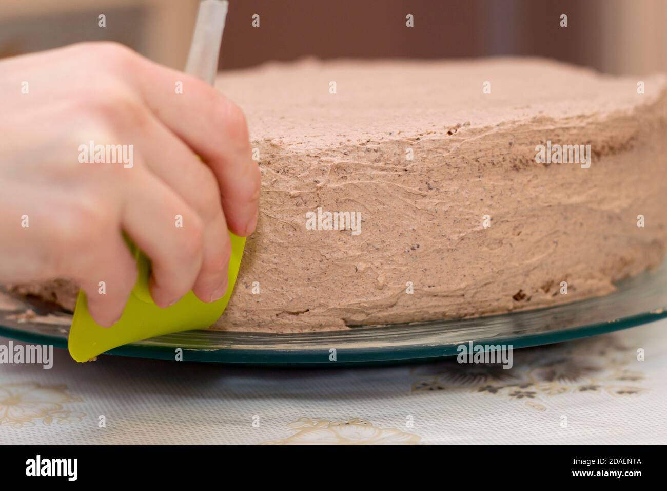 Arbeitsprozess des Backens Kuchen zu Hause. Nahaufnahme der weiblichen Hand Dekoration Creme auf Schokolade Keks. Kulinarisches und köstliches Dessertkonzept. Stockfoto