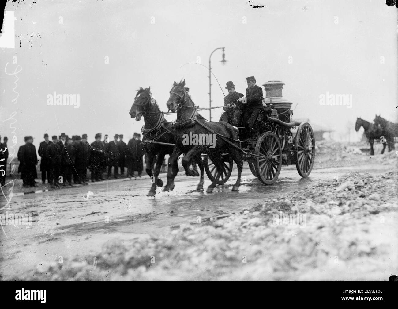 Feuerwehrmann-Test, Mann, der einen von Pferden gezogenen Feuerwehrmann in einer Stadtstraße fährt Stockfoto