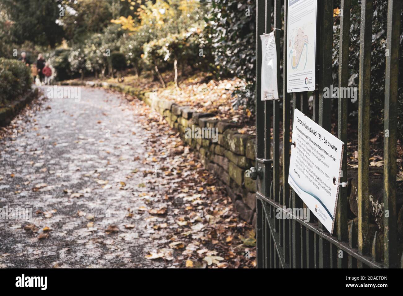 Soziale Distanzierungsschilder an Parktoren, mit Herbstblättern im Hintergrund. Aufgenommen in Grosvenor Park, Chester. Stockfoto