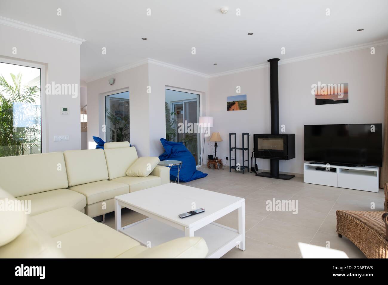 Modernes, sauberes Wohnzimmer des Luxus-Familienhauses mit großem L-förmigen Ledersofa und Fliesenböden Stockfoto