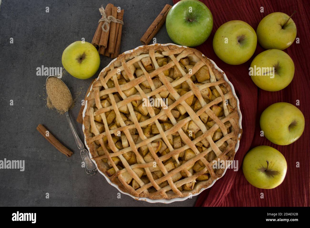 Apfelkuchen auf rotem Stoffhintergrund. Schön dekorierte Torte Draufsicht Foto. Hausgemachter Dessertkuchen. Stockfoto
