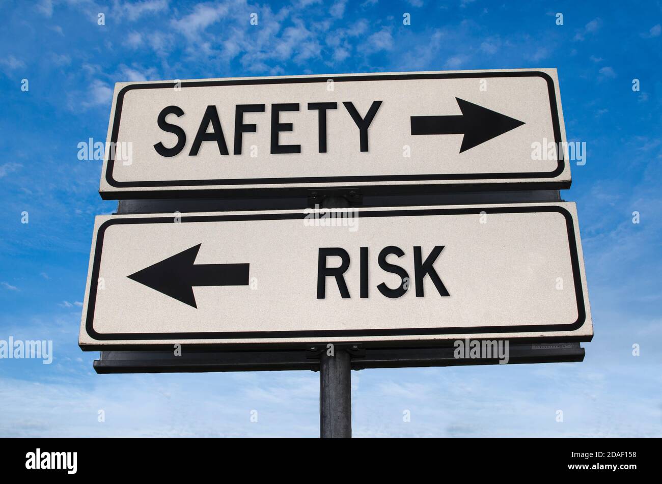 Sicherheit und Risiko weiß zwei Pfeile Zeichen auf Metallstange. Richtungsstraße. Kreuzung Straßenschild, zwei Pfeile vor blauem Himmel Hintergrund. Zwei Wege Stockfoto