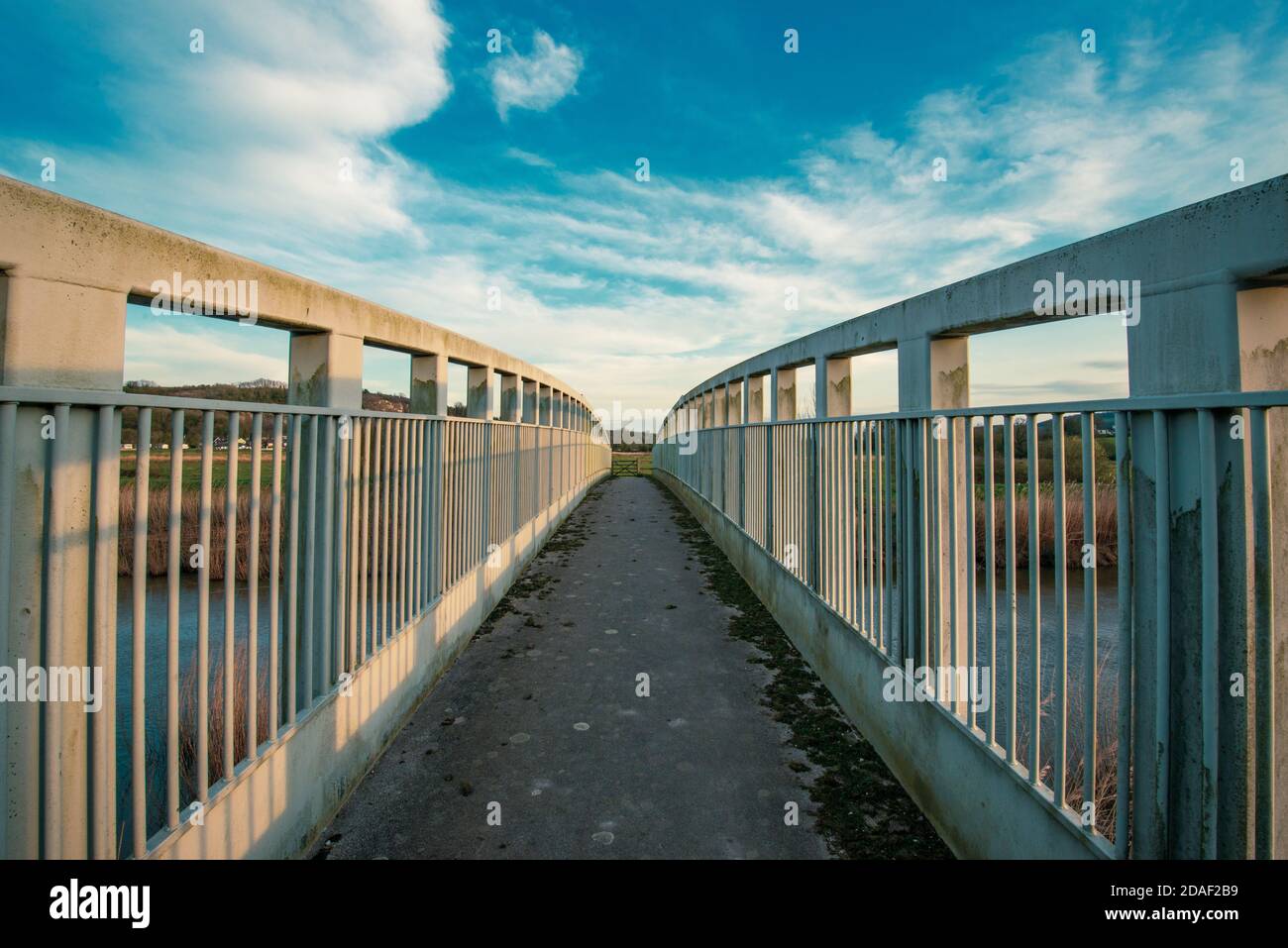 Abendszene in West Sussex bei Bury. Eine Metallbrücke für Wanderer über den Fluss Arun. Stockfoto