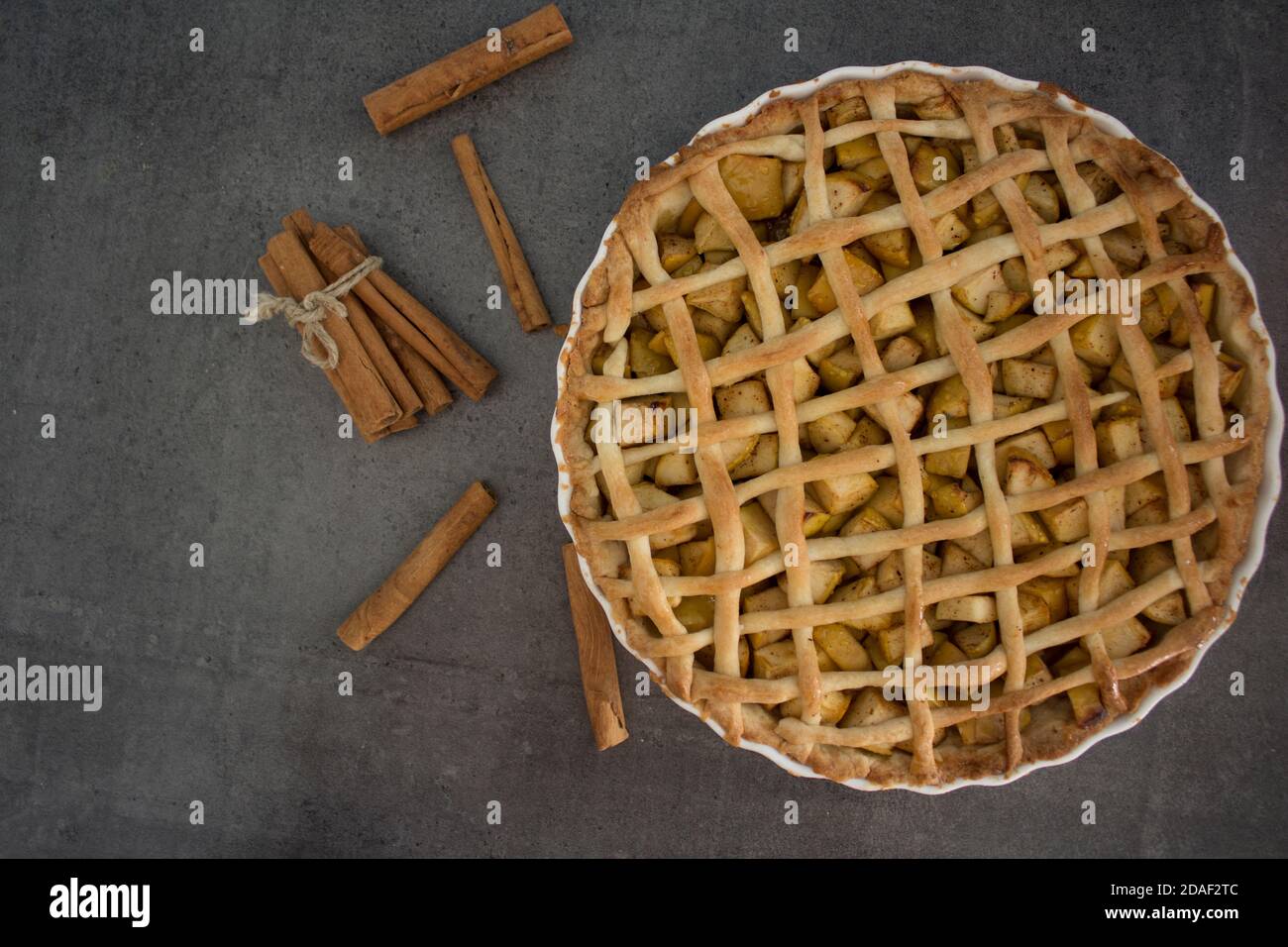 Frische Äpfel, Zimtstangen und klassische amerikanische Pie Draufsicht Foto. Grauer Hintergrund mit Kopierbereich. Stockfoto
