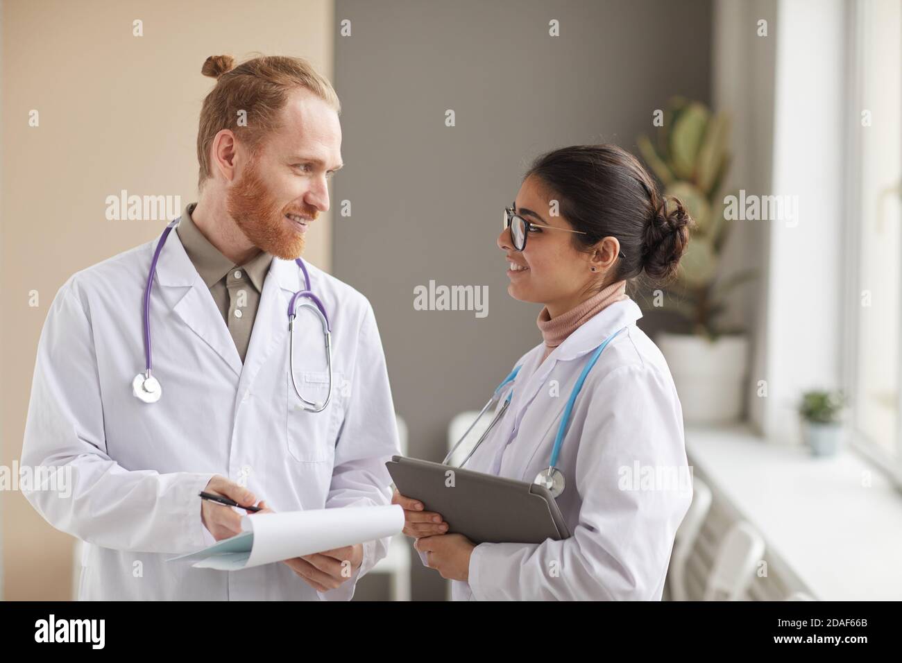 Zwei Ärzte in weißen Mänteln diskutieren Krankheit zusammen im Stehen Auf dem Flur im Krankenhaus Stockfoto