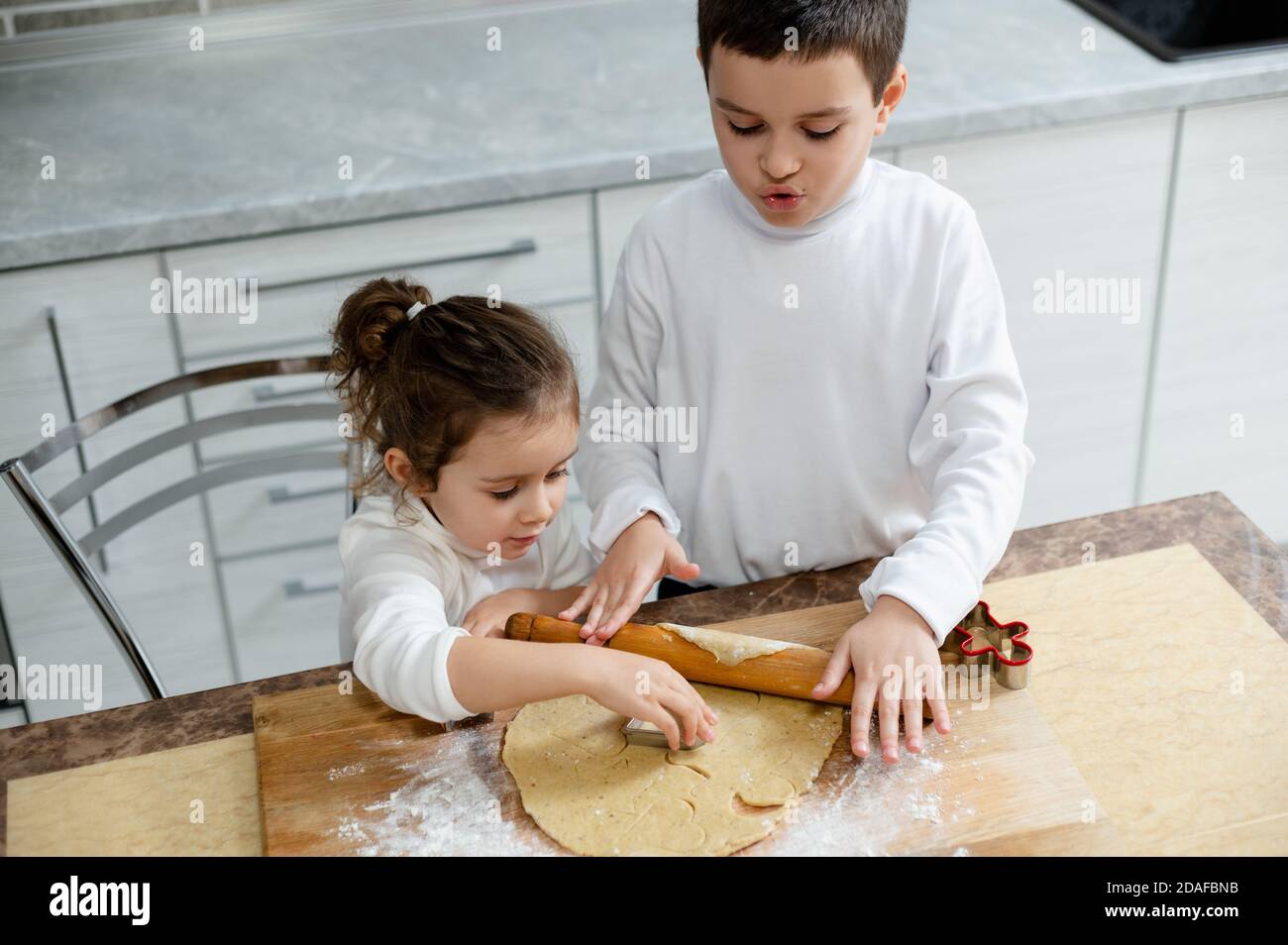 Die Kinder werden aus dem tesca der Rohlinge für Weihnachtskekse mit