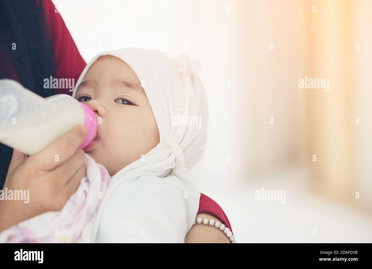 Muslimische Mutter füttert ihr Baby mit einer Flasche Milch. Stockfoto