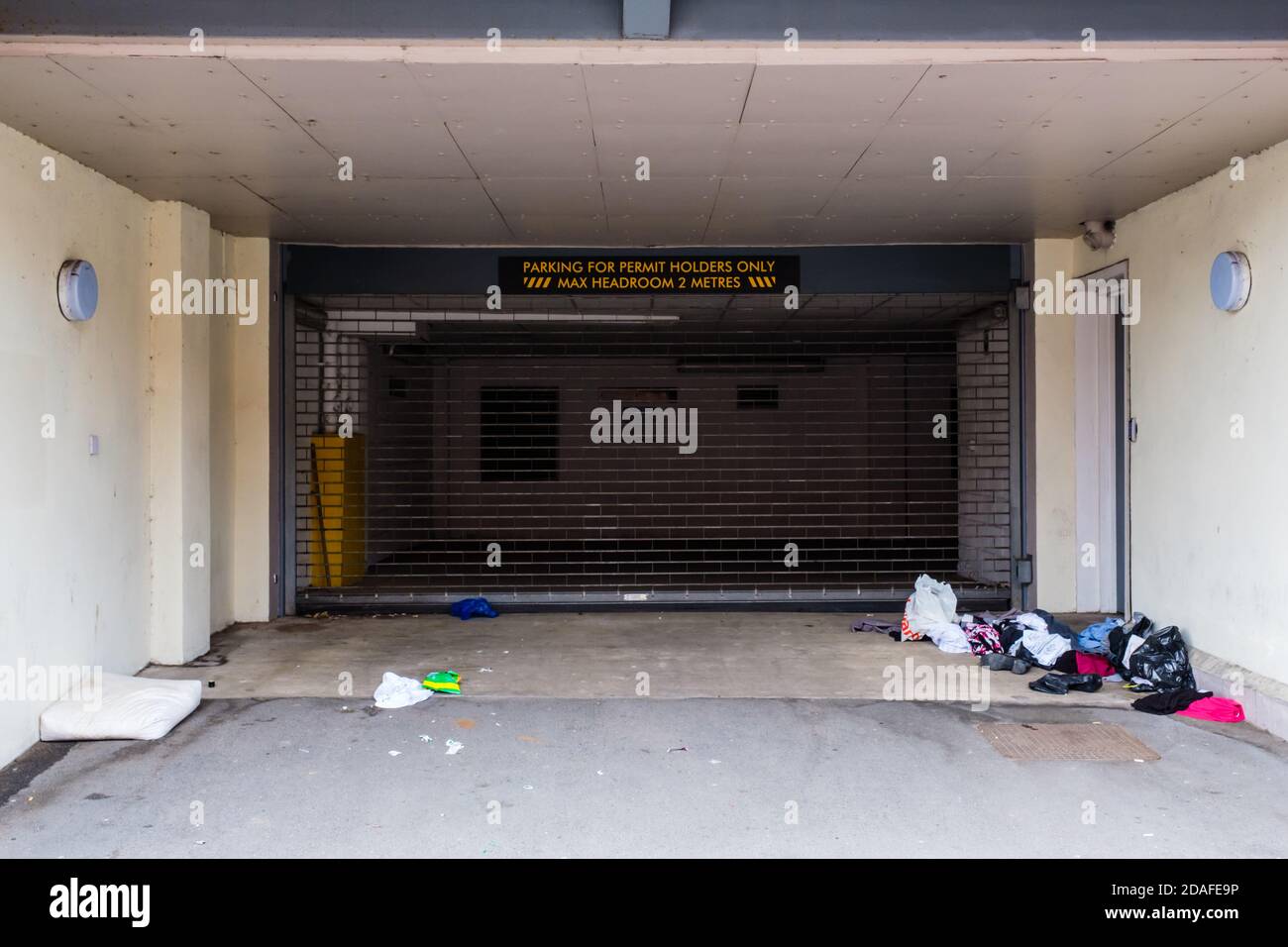 Die Habseligkeiten von jemandem, der rau schlief, blieben im Eingang Zu einer Garage Stockfoto