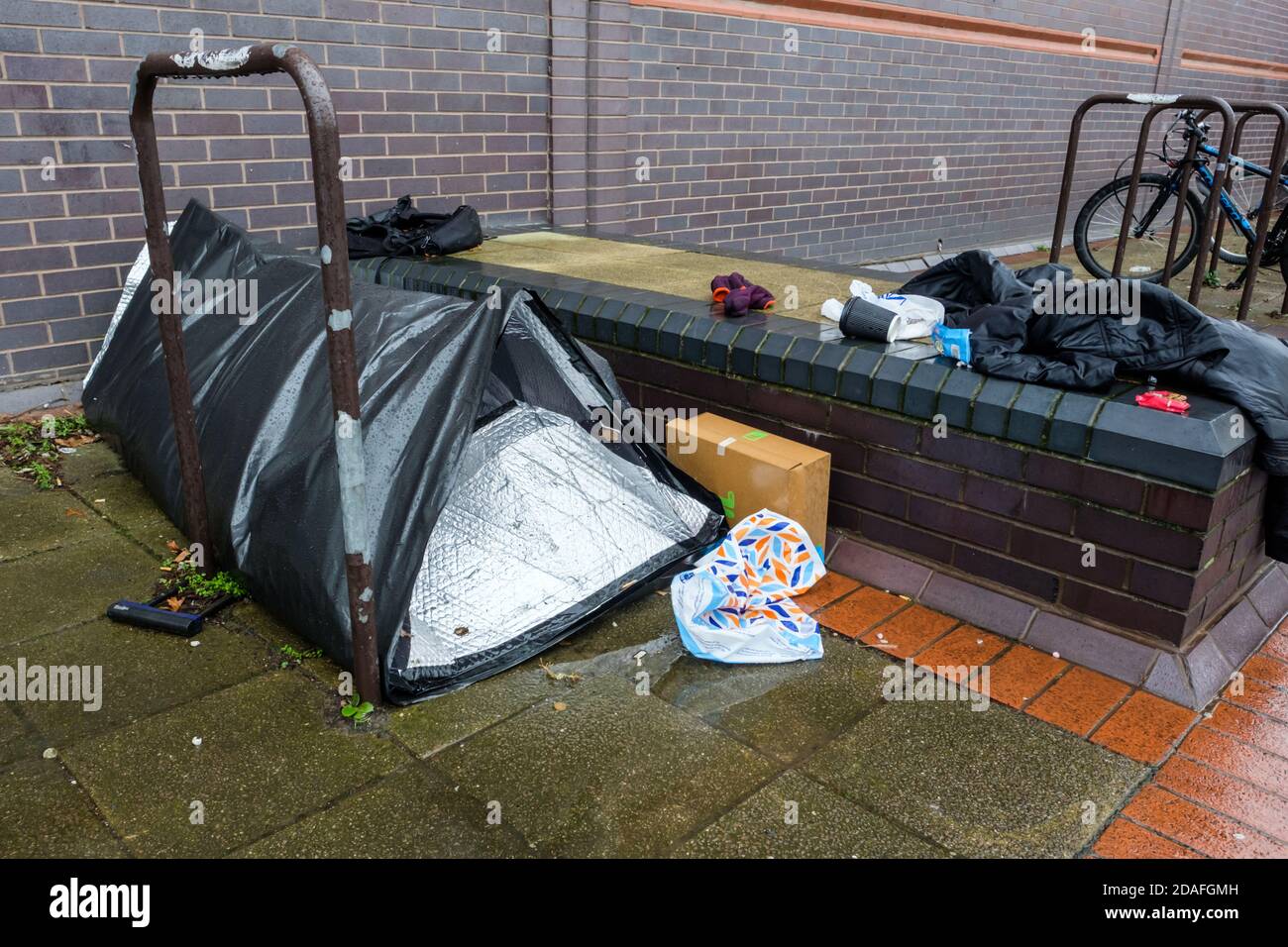 Ein Pod Zelt und die Habseligkeiten von jemandem, der im Regen und auf der Straße schlecht schläft. Stockfoto