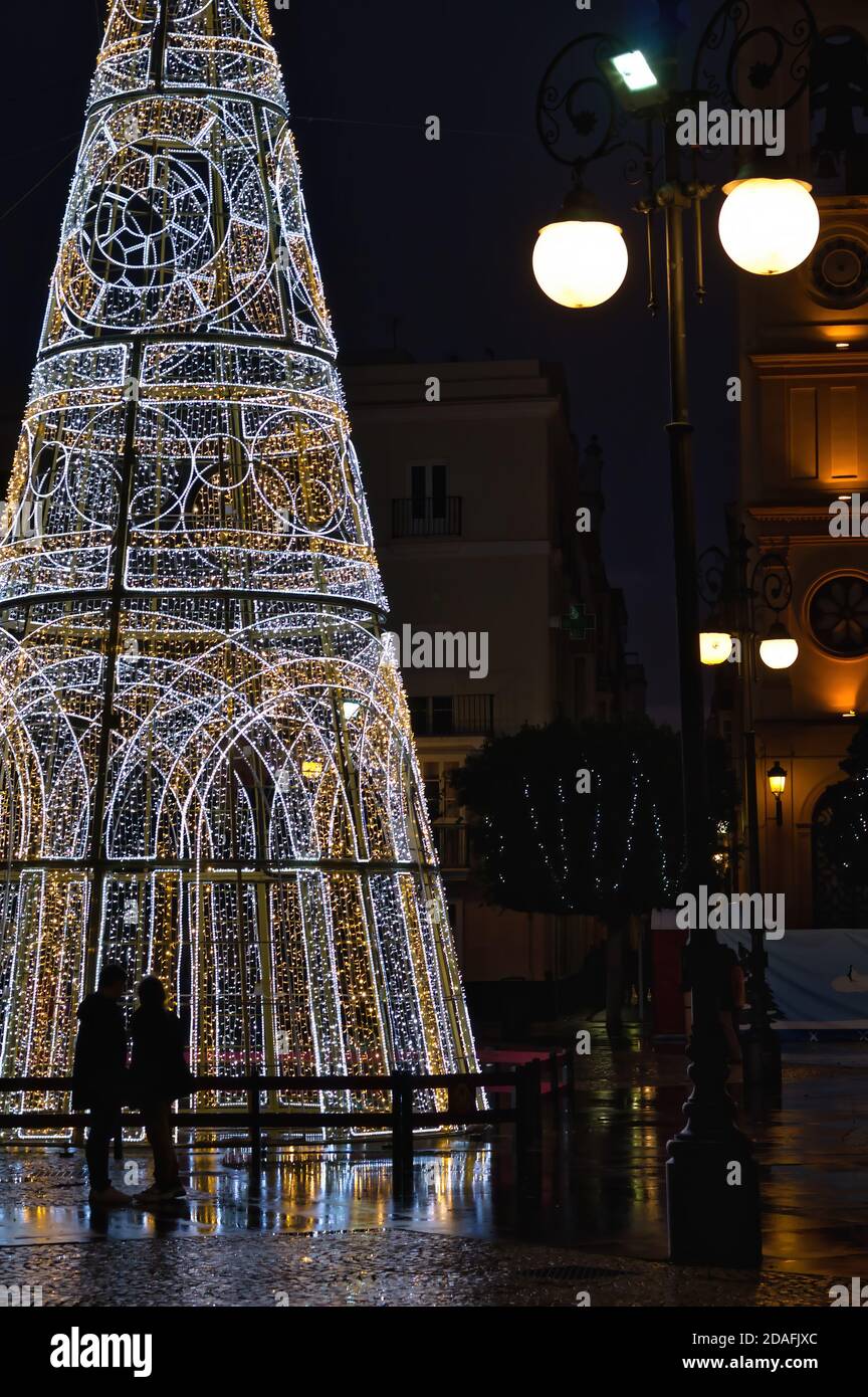 Ein Paar bewundert einen großen Weihnachtsbaum auf einem Platz in Cadiz, Spanien. Stockfoto