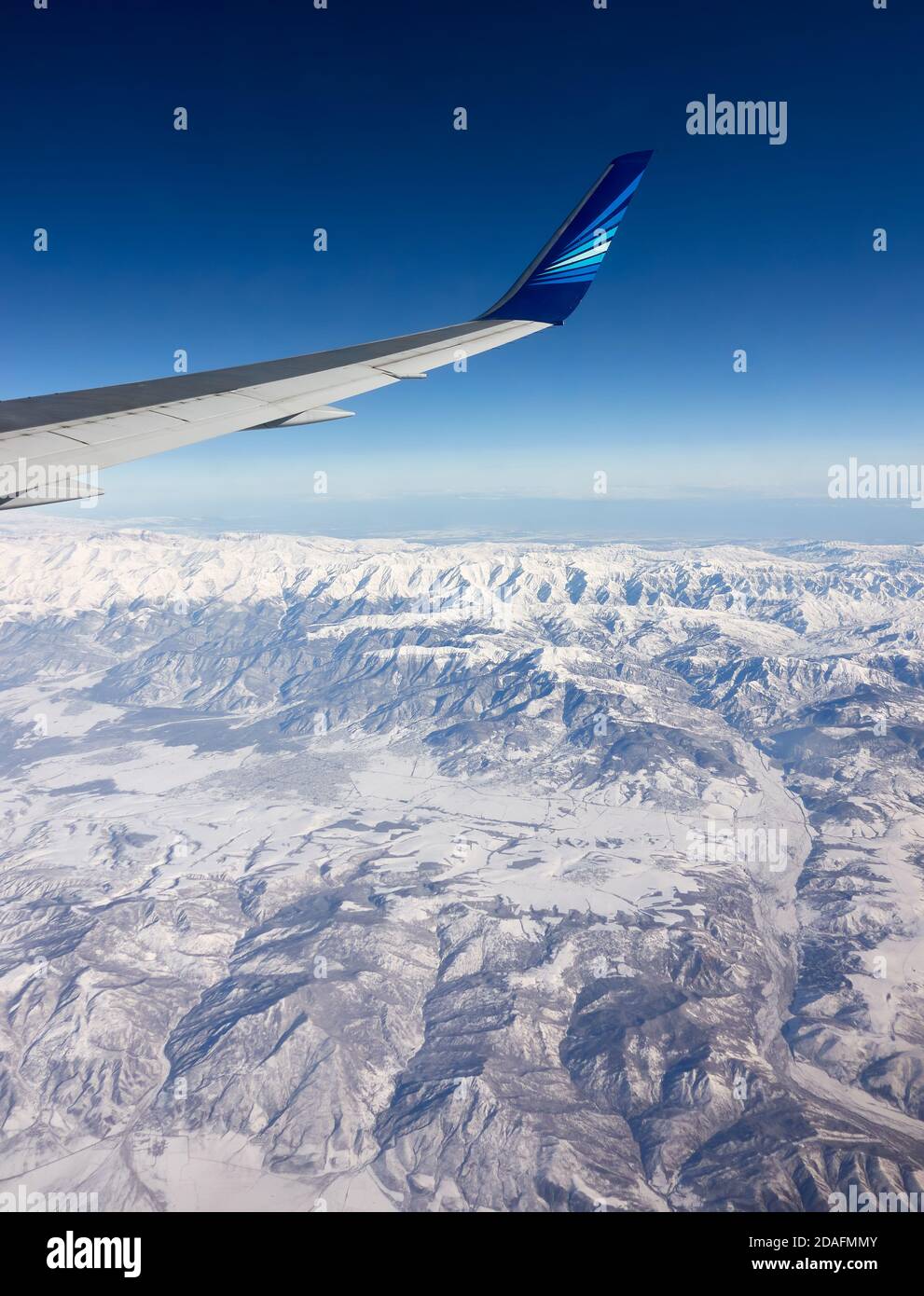 Caucasus Range, Aserbaidschan - 12. Februar 2020: Azerbaijan Airlines Passagierflugzeugerflügel mit Firmenlogo über der Greater Caucasus Range mit s Stockfoto