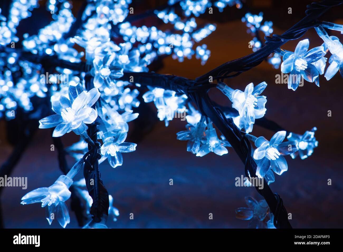 Nahaufnahme von Zweig künstlichen Baum mit LED-Blumen Kirsche, blaues Licht Girlande, selektive Fokus Stockfoto
