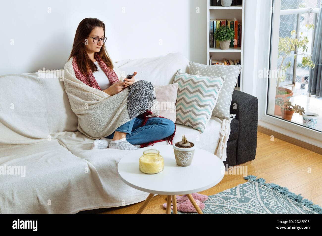 Mädchen zu Hause entspannen auf dem Sofa mit einem Handy in den Händen. Stockfoto