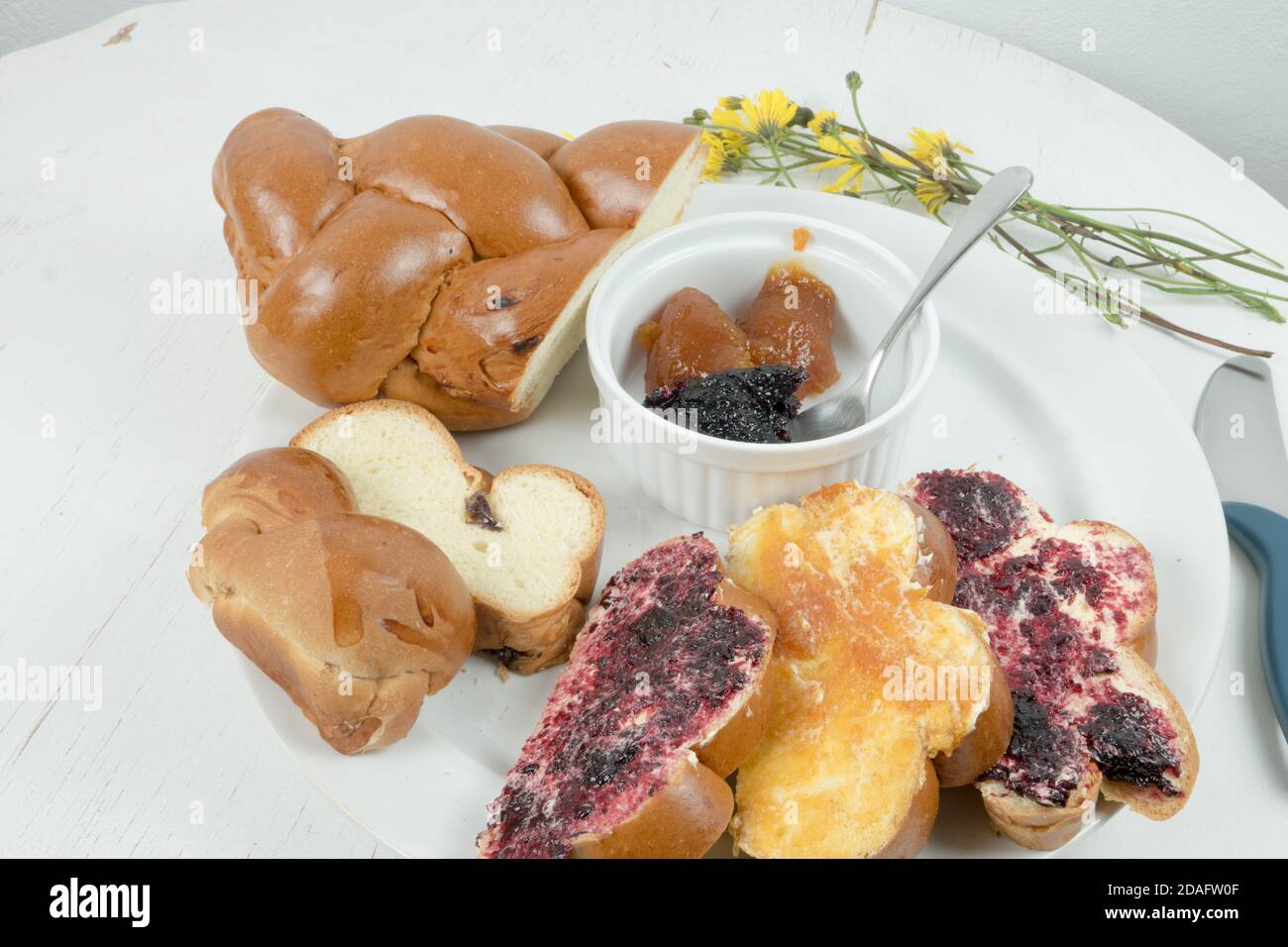 Traditionelles weihnachtsbrot aus der Slowakei. Weihnachtsbäckerei mit Butter, hausgemachte Marmelade serviert auf alten runden weißen Holztisch. Dekoriert mit Blumen Stockfoto