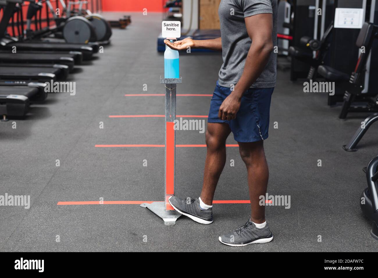 Mittelteil von fit afroamerikanischen Mann, der seine Hände desinfiziert Im Fitnessraum Stockfoto