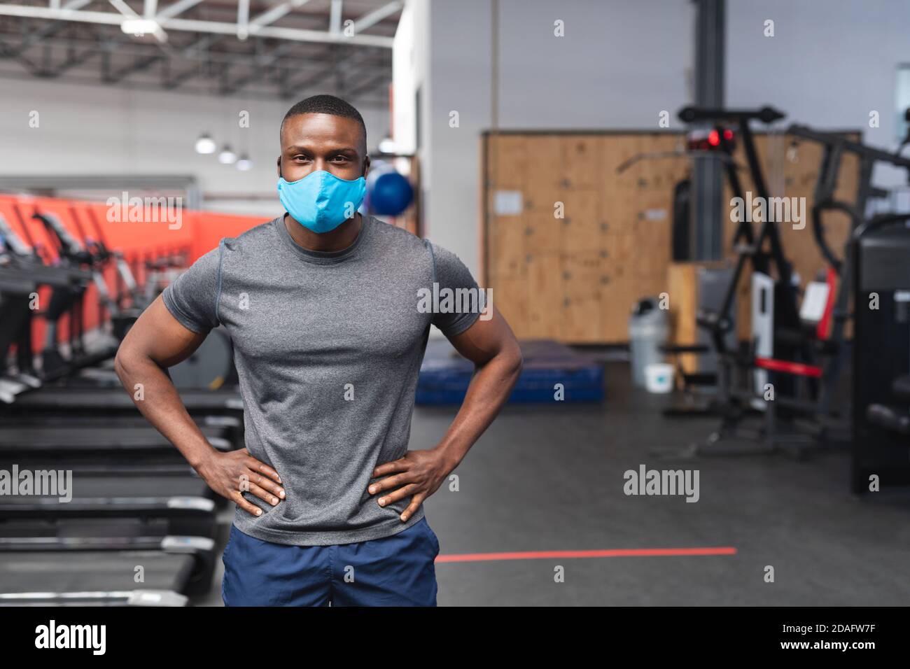 Portrait von fit afroamerikanischen Mann trägt Gesichtsmaske stehen Im Fitnessraum Stockfoto