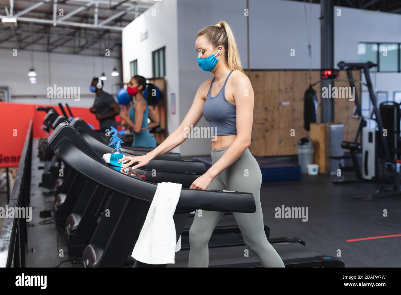 Fit kaukasische Frau trägt Gesichtsmaske läuft auf Laufband tun Cardio-Training im Fitnessstudio Stockfoto
