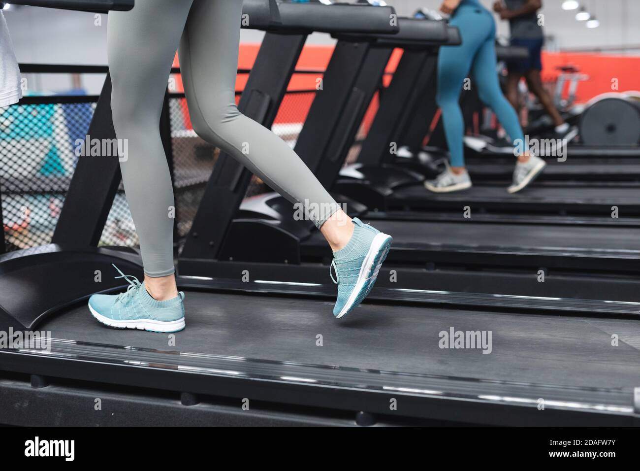 Mittelteil der fit kaukasischen Frau trägt Gesichtsmaske laufen Auf dem Laufband tun Cardio-Training in Th Stockfoto
