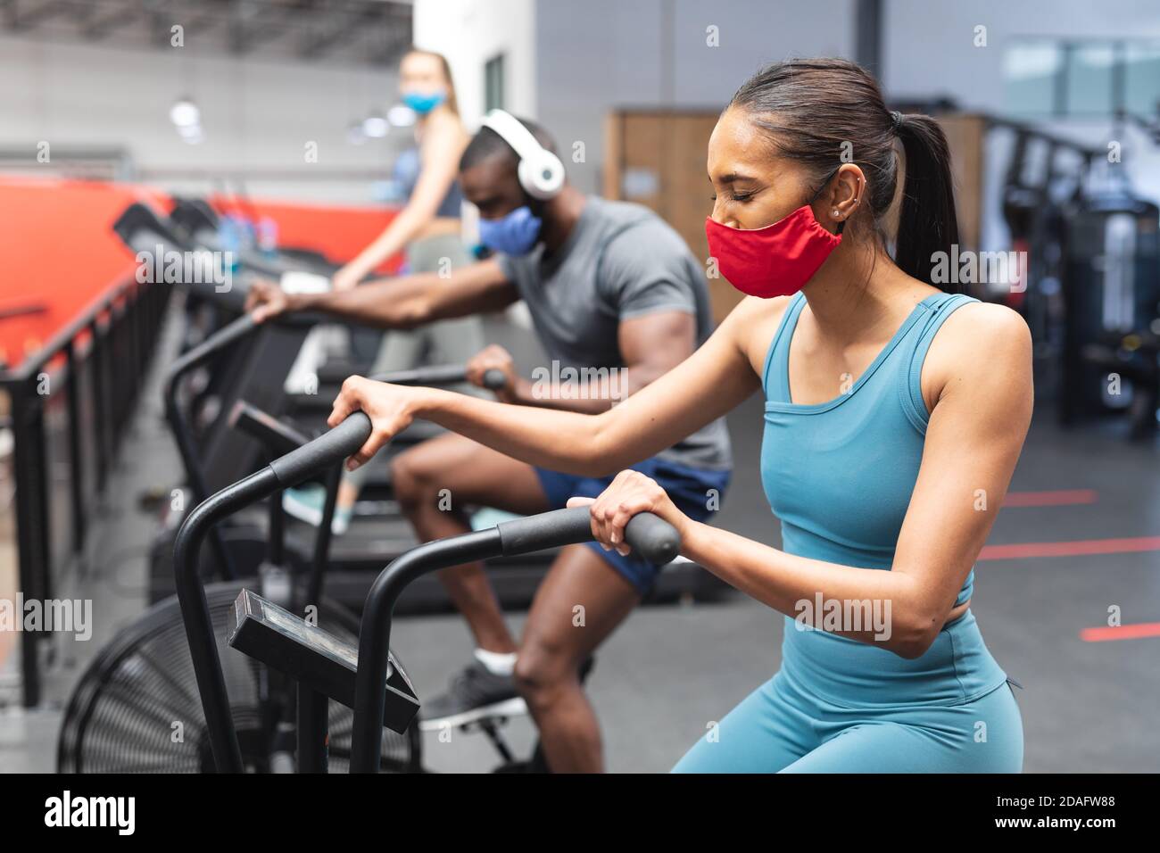 Fit afroamerikanischen Mann und fit kaukasischen Frau trägt Gesicht Masken Training auf Heimtrainer in Stockfoto