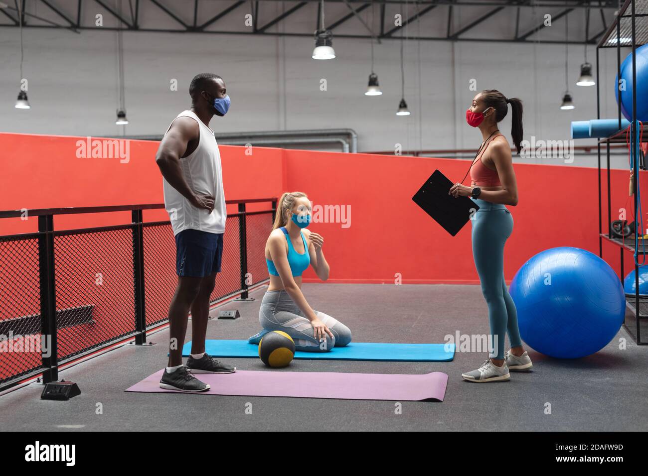 kaukasische weibliche Fitness-Trainer hält Stoppuhr und Zwischenablage instructing fit afroamerikanische m Stockfoto