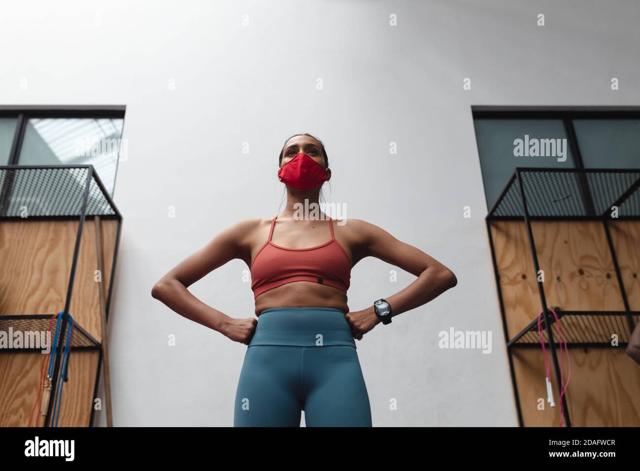 Passen kaukasische Frau trägt Gesichtsmaske stehen mit der Hand auf Ihre Taille im Fitnessstudio Stockfoto
