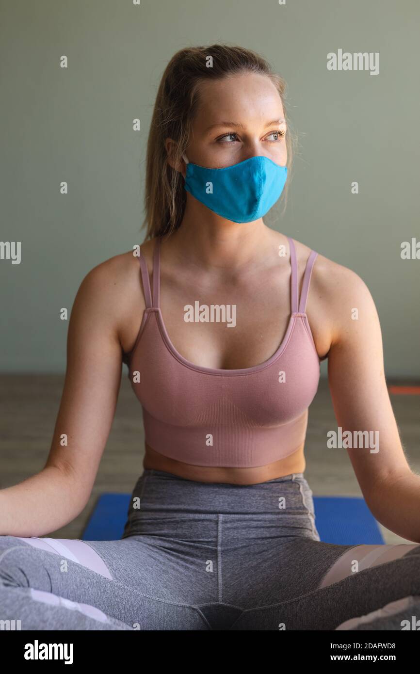 Mittlere Abschnitt der fit kaukasischen Frau trägt Gesichtsmaske üben Yoga im Fitnessstudio Stockfoto