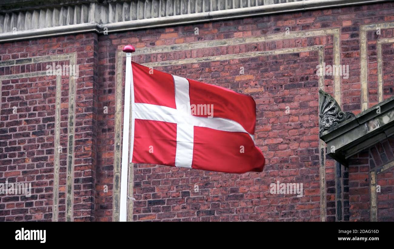 Dänische Flagge mit Backsteinmauer Hintergrund in kopenhagen, Dänemark. Stockfoto