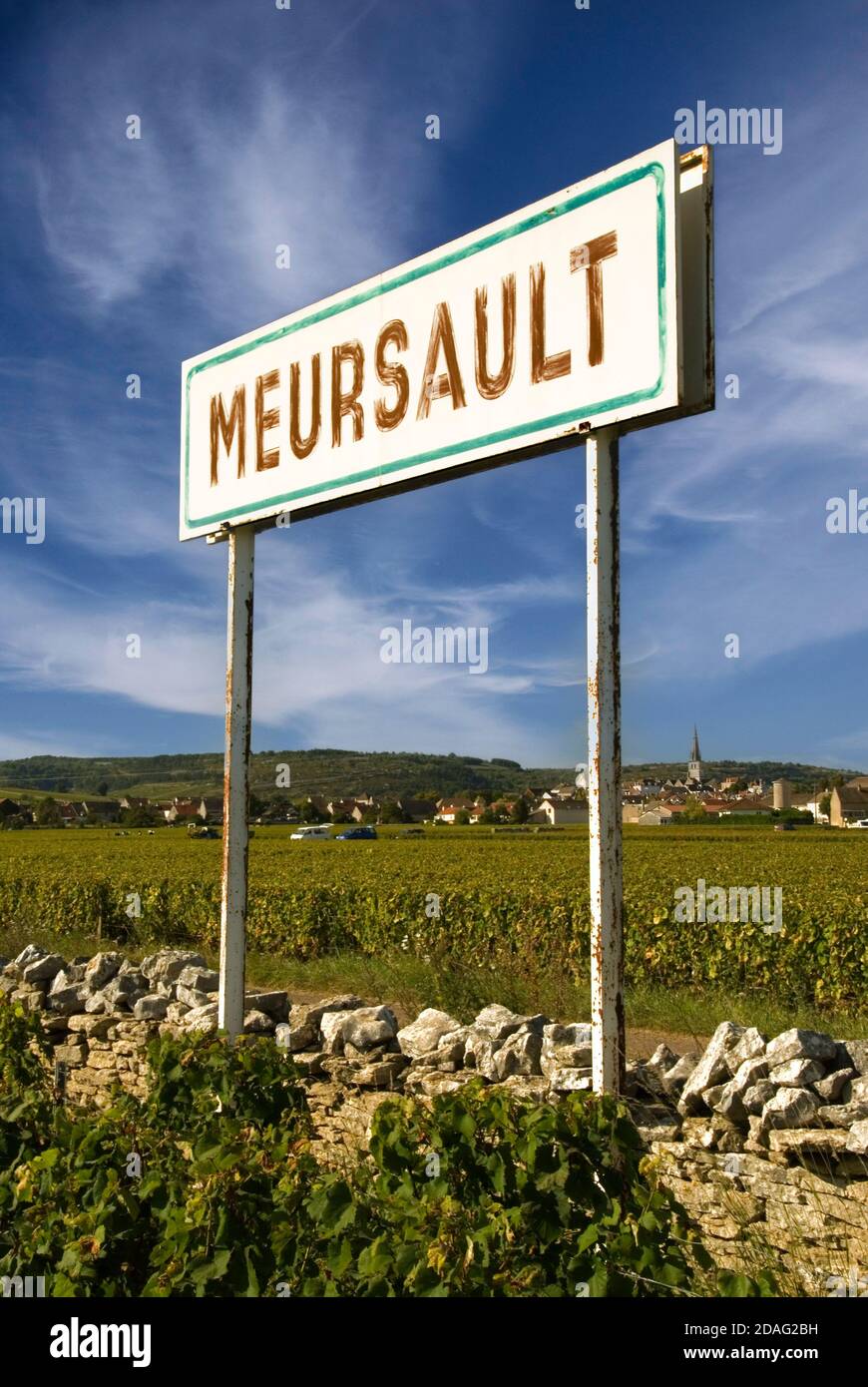 Meursault rustikales Weindorf Grenzschild mit burgunderroten Weinbergen, Dorf und Kirche dahinter, Cote d'Or. Frankreich Stockfoto