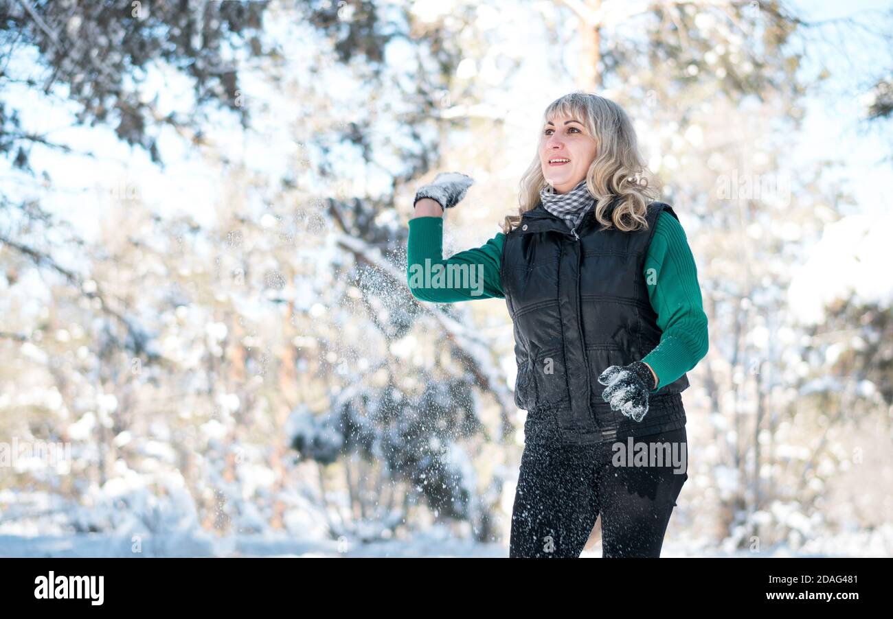 Frau spielt mit Schnee im Winterwald. Stockfoto