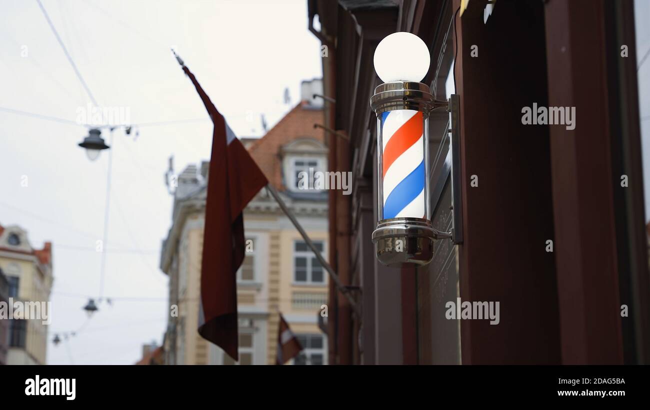 Leuchtend rot weiß blau Barbershop Stange an der Wand mit LV Flagge im Hintergrund Stockfoto