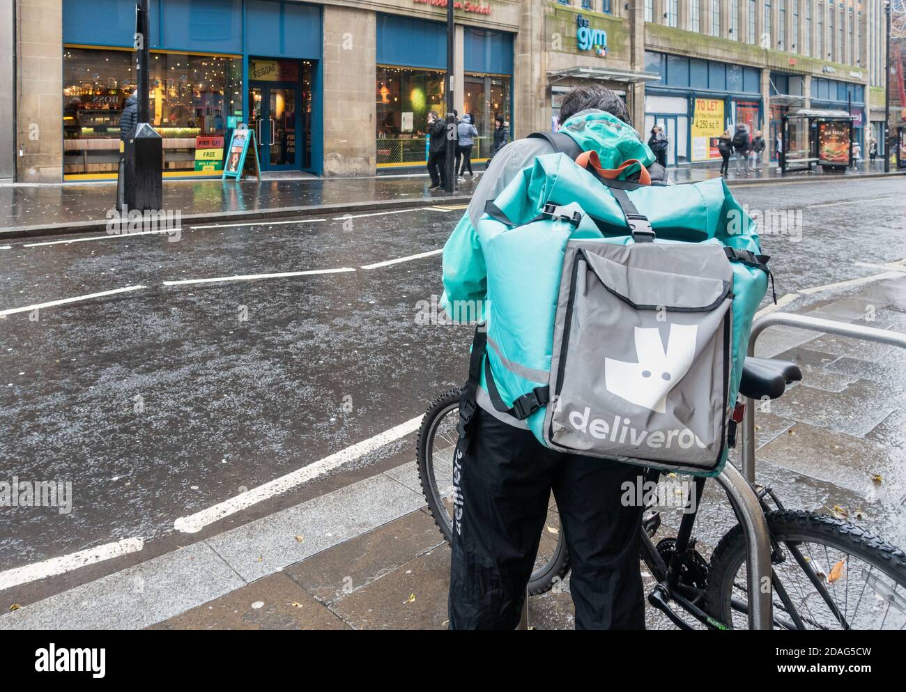 Deliveroo Rider, Kurier mit Fahrrad im Regen in Newcastle upon Tyne, England. VEREINIGTES KÖNIGREICH Stockfoto