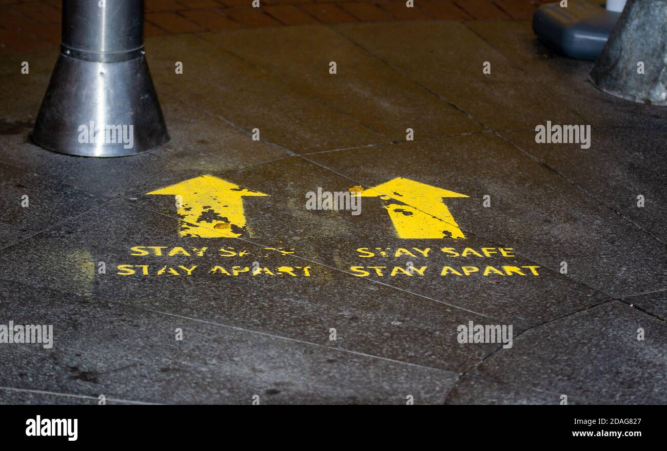 Stay Safe Stay Apart schablonierte gelbe Straßenschilder für soziale Distanzierung in Birmingham, Großbritannien Stockfoto