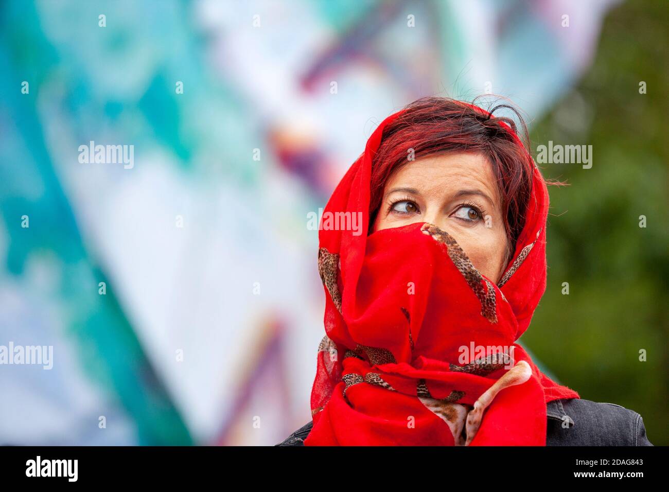 Eine attraktive Frau mittleren Alters trägt einen roten Kopfschal über Kopf und Gesicht während eines Extinction Rebellion Protestes vor Shell UK Hauptquartier. Stockfoto